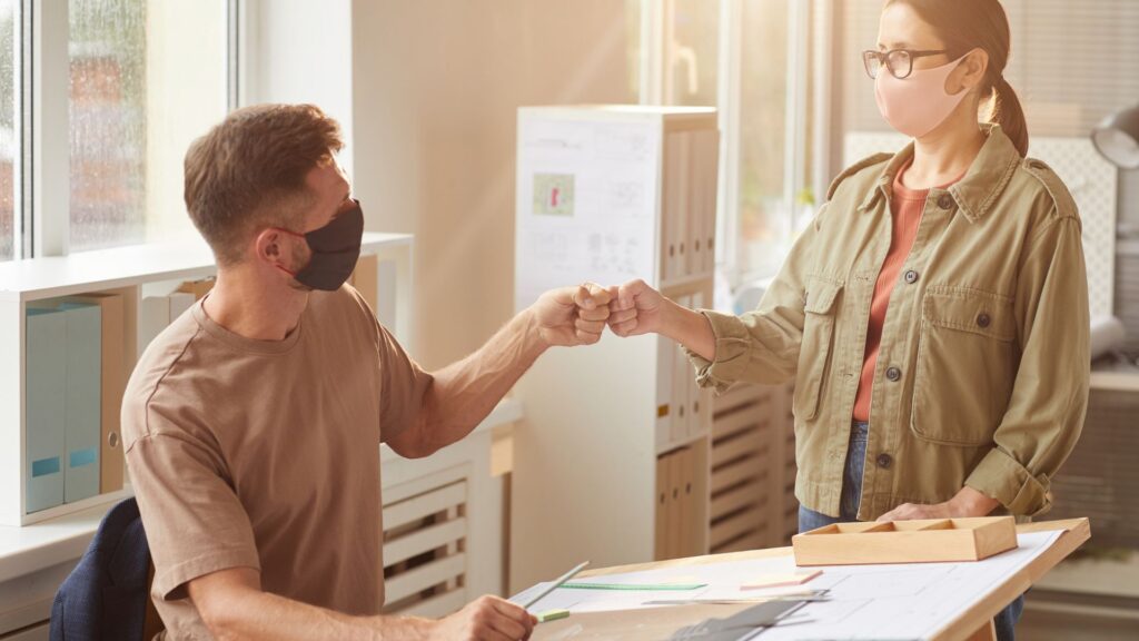 One To One Meeting Giving Thumbs Up With Mask on Face On WorkDesk
